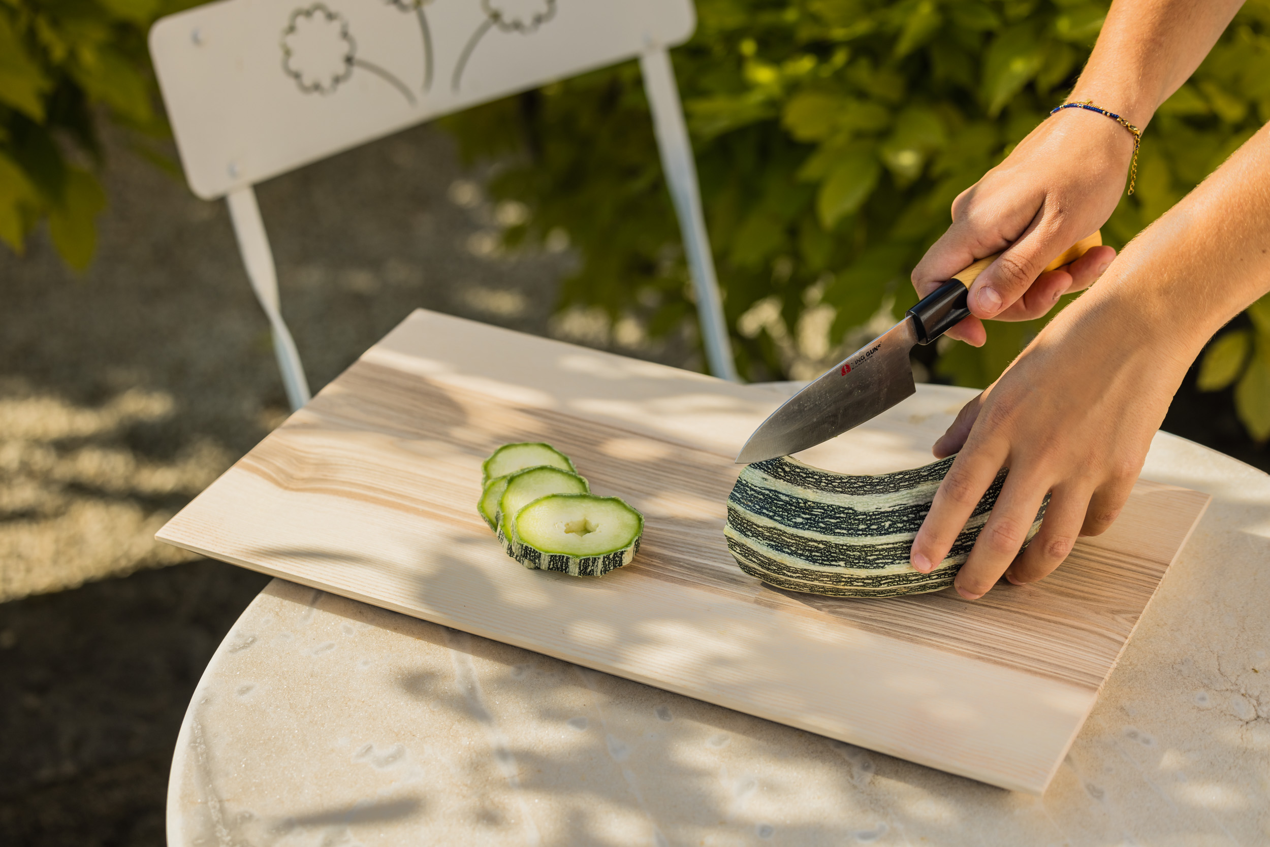 Planche à découper contemporaine, grand modèle, découpe de courgette dans le jardin.