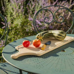Planche à découper avec manche, modèle xxl. Découpe de tomates et courgettes dans un jardin.